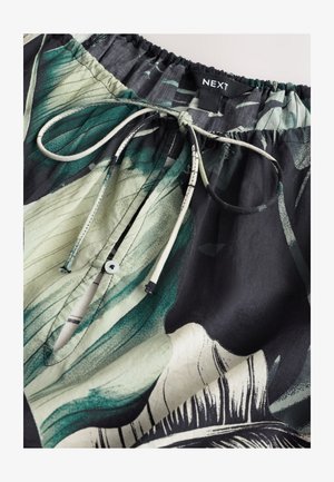 Nahaufnahme eines elastischen Bunds mit floralem grünen, schwarzen und weißen Stoff, mit gebundenem Kordelzug und geknöpftem Schlüsselloch-Öffnung.