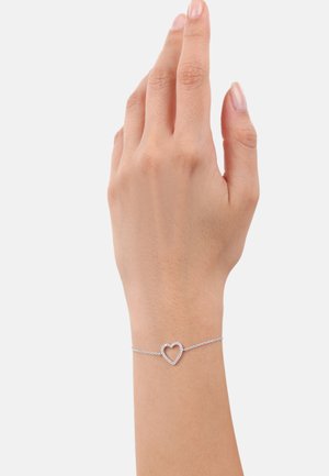 Bracciale in argento con un charm a forma di cuore al centro, design minimalista, superficie liscia e link delicati.