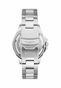 Orologio in acciaio inossidabile argento con bracciale a maglie lucide, chiusura prominente e logo inciso. Il fondello trasparente mostra il movimento.