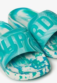 Turquoise slide sandals with a marbled pattern, featuring a wide strap with raised "SUPER" lettering, textured footbed, and solid white sole.