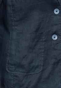 Námořnický modrý lněný blejzr s náprsní kapsou a dvěma knoflíky, s jemným leskem, který zvýrazňuje texturovaný povrch látky.