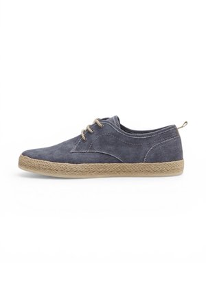 Sneaker casual basso con tomaia in tela grigia, suola beige intrecciata avvolta in juta, quattro occhielli e lacci beige su sfondo bianco.
