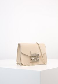 Borsa in pelle beige con finitura testurizzata, dettagli in metallo color oro, chiusura magnetica e tracolla a catena. Forma rettangolare con patta a ribalta.