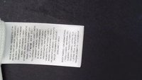 Étiquette de vêtement avec un texte multilingue indiquant « Made in India » et des informations sur le tissu sur une étiquette blanche sur fond sombre.