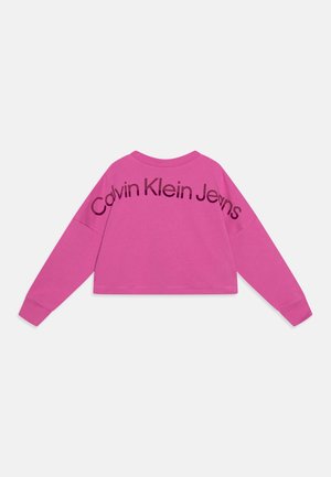 Sweat-shirt court à manches longues de couleur rose vif avec l'inscription "Calvin Klein Jeans" en grandes lettres noires au dos.