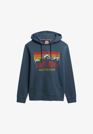 Sudadera de algodón azul con un bolsillo tipo canguro en el frente, capucha con cordón y un diseño gráfico que presenta montañas y "Superdry Outdoor" en colores vivos.