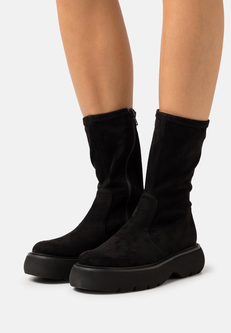 Bottes en daim noir mi-mollet avec une finition texturée, dotées d'une fermeture éclair latérale et d'une semelle en caoutchouc épaisse avec un motif en relief.