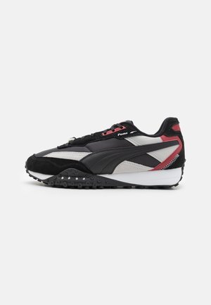 Baskets Puma noires, grises et rouges avec semelle texturée, fermeture à lacets et logo Puma sur le côté.