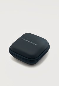 Συμπαγής μαύρη θήκη μεταφοράς με φερμουάρ και λογότυπο Tommy Hilfiger στην κορυφή, σχεδιασμένη για την αποθήκευση μικρών αξεσουάρ ή ηλεκτρονικών.