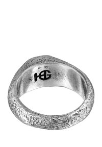 Silverring med texturerad yta, med en slät inre band. Markeringar inkluderar "925" och en logotyp inuti.