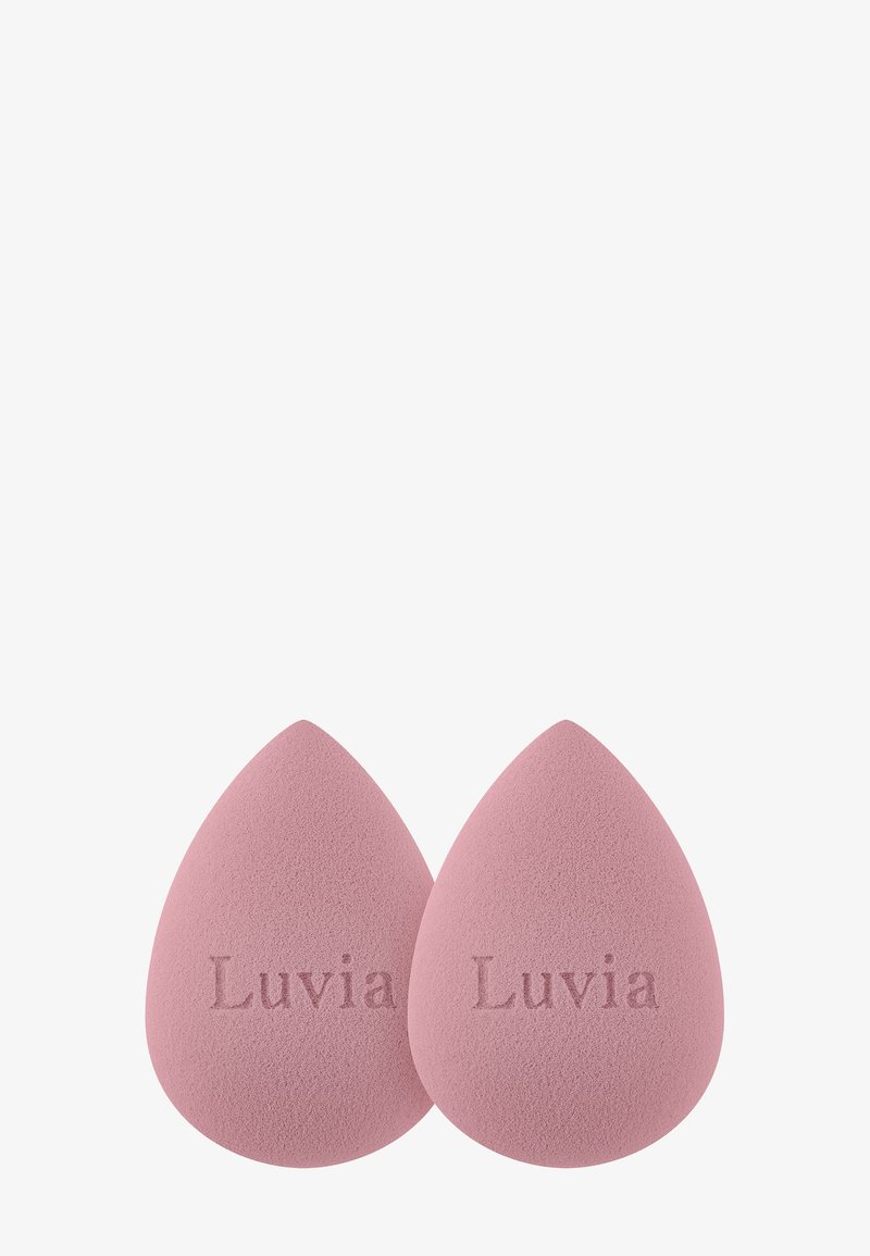 Deux éponges à maquillage roses en forme de goutte, avec une texture mate et le logo "Luvia" embossé sur un côté. Surface lisse pour l'application.