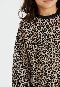 Sweater a stampa leopardata con maniche lunghe, caratterizzato da un collo a costine nero, una texture morbida e una miscela di toni beige, neri e marroni.
