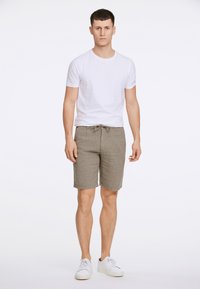 Pantalones cortos grises con patrón y cintura ajustable, combinados con una camiseta blanca sencilla y zapatillas blancas. Tejido suave y diseño de corte recto.