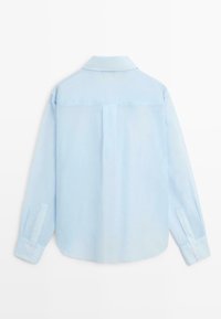 Chemise bleu clair à manches longues vue de dos avec un col, un pli au centre et des poignets boutonnés.