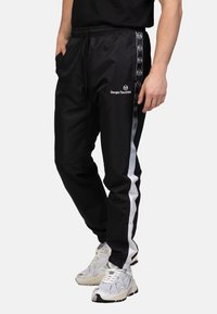 Zwarte sportbroek met een trekkoord in de taille, voorzien van witte zijstrepen en een logo. Gemaakt van soepel, lichtgewicht materiaal.