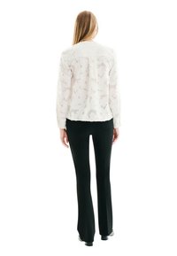 Blouse blanche texturée avec un motif subtil, de coupe droite et aux manches longues. Associée à un pantalon noir ajusté, créant un look épuré.