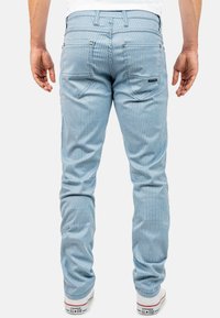 Lichtblauwe gestreepte denim jeans met een slim fit, voorzien van twee achterzakken en afgewerkt met witte sneakers.