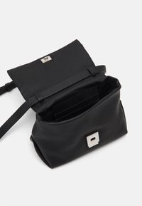 Černá crossbody taška z texturované kůže se stříbrnou obdélníkovou sponou, otevřenou klopou a viditelnými vnitřními přihrádkami na karty na bílém pozadí.