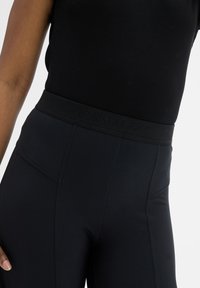 Zwarte high-waisted leggings met een gemêleerde tailleband met reliëfbranding, een gladde stof en zijnaaddetails.