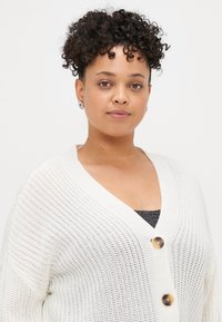 Weißer gestrickter Cardigan mit V-Ausschnitt, ausgestattet mit zwei großen goldenen Knöpfen, offener Webstruktur und entspannter Silhouette.