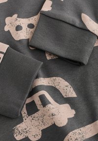 Felpa grigia con polsini a costine, decorata con motivi di veicoli rosa e mucche, che presenta una texture morbida e un design casual.