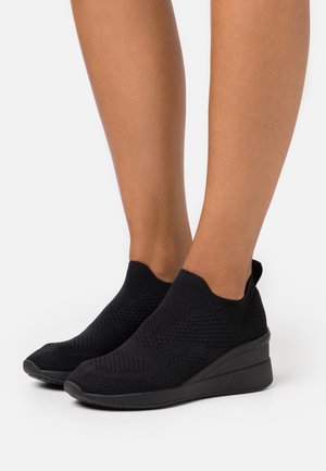 Schwarze Stricksneaker mit glatter Textur, Schlupf-Design und Keilabsatz. Verfügt über ein atmungsaktives Obermaterial und minimalistische Akzente.