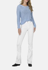 Maglione a maglia azzurro chiaro con maniche lunghe e scollatura rotonda; abbinato a pantaloni bianchi a zampa d'elefante; indossato con stivali neri alla caviglia.