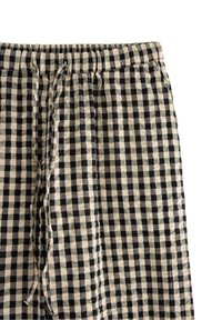 Czarno-beżowe szorty w kratkę wykonane z lekkiego materiału. Posiadają elastyczny pas z sznurkiem i boczne kieszenie.
