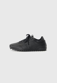 Black sneaker made of smooth leather, featuring a rounded toe, textured sole with grip, and lace-up design. Logo embossed on side.