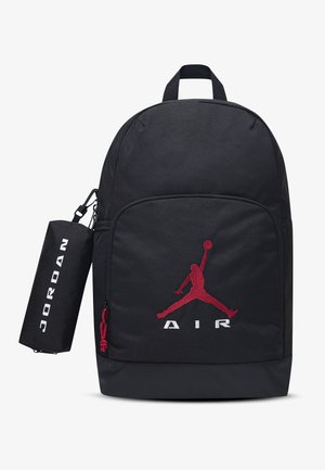 Sac à dos noir avec logo Jumpman rouge à l'avant et texte "AIR", avec une pochette cylindrique latérale étiquetée "JORDAN".