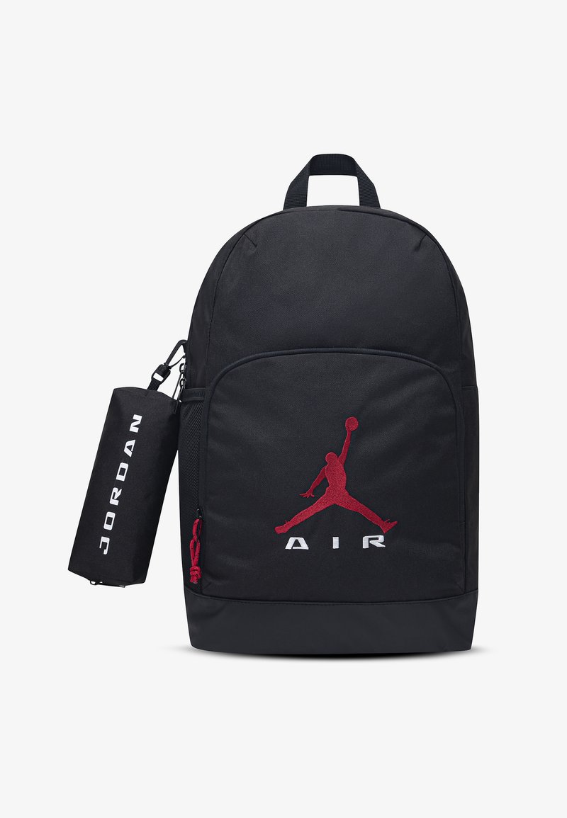 Μαύρο σακίδιο πλάτης με κόκκινο λογότυπο Jumpman μπροστά και το κείμενο "AIR", που διαθέτει κυλινδρική θήκη στο πλάι με την ετικέτα "JORDAN".