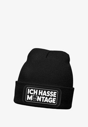 Black knitted beanie with ribbed texture. Features a rectangular patch with white text "ICH HASSE MONTAGE" and a cat illustration.