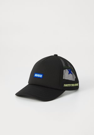 Black cap with a structured front, mesh back, blue "HUGO" logo, green "IGNITE THE NIGHT" text, and a small blue star accent on the side.