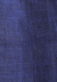 Primo piano di tessuto blu scuro a trama fitta con una texture ruvida e fili intrecciati visibili.