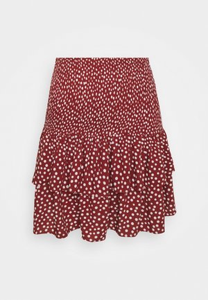 Punainen pilkullinen hame, jossa on kerroksellinen röyhelösuunnittelu, valmistettu kevyestä kankaasta, jonka pinta on sileä, täydellinen lämpimiin säihin.