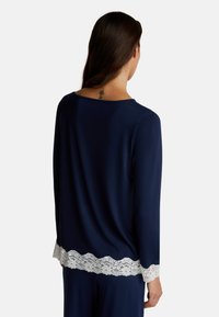 Maglietta a maniche lunghe blu navy con scollatura ampia e bordo in pizzo bianco, caratterizzata da una texture morbida e una vestibilità rilassata.
