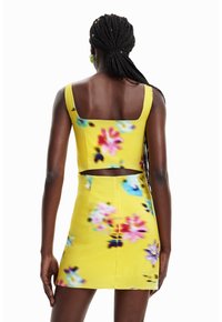 Top corto floral amarillo y falda corta con una silueta ajustada. Presenta un escote cuadrado y un detalle recortado sobre la cintura.