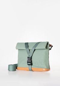 Borsa impermeabile verde con chiusura a rotolo, tracolla regolabile, fondo arancione e logo in rilievo. Dotata di una fibbia in plastica nera.