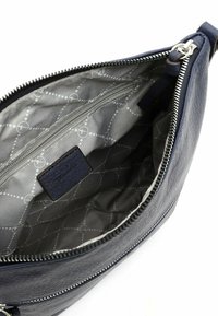 Interno della borsa in pelle blu con fodera trapuntata grigia, chiusura con zip e tasche interne per l'organizzazione; dettaglio di branding minimale visibile.
