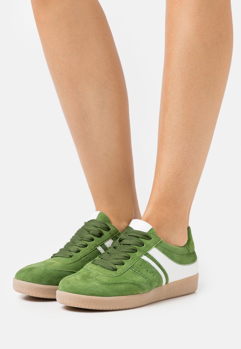 Baskets en daim vert avec des accents blancs, bout rond et semelle épaisse en caoutchouc. Dotées de lacets verts et de détails cousus sur la tige.