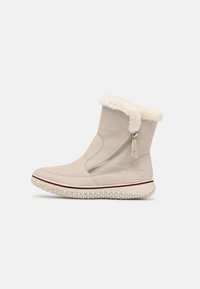 Stivale invernale beige con zip laterale, foderato in morbido pelo bianco, suola con texture e punta rotonda su uno sfondo bianco.