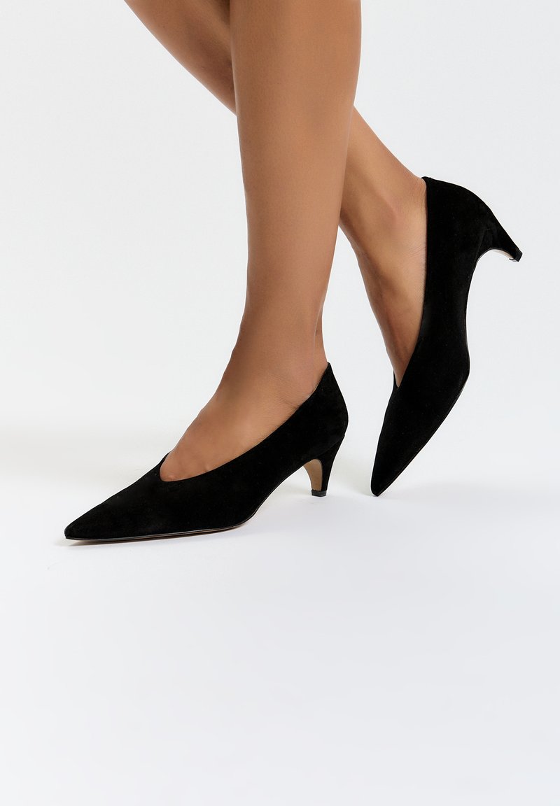 Schwarze Wildlederschuhe mit hohen Absätzen, spitz zulaufend und im V-Ausschnitt-Design, mit einem kleinen Kegelhaken und glatter Textur.