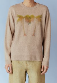 Pull beige en maille avec un col rond et des manches longues. Présente un motif abstrait coloré sur le devant, mélangeant des nuances de jaune et de rose.
