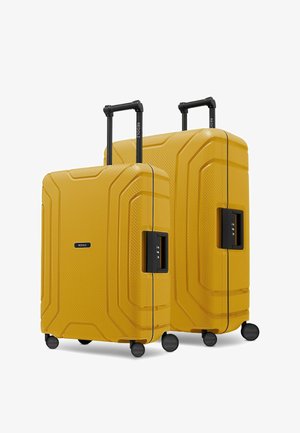 Deux valises rigides jaunes avec des surfaces texturées, des poignées rétractables noires, quatre roues et des serrures à combinaison intégrées.