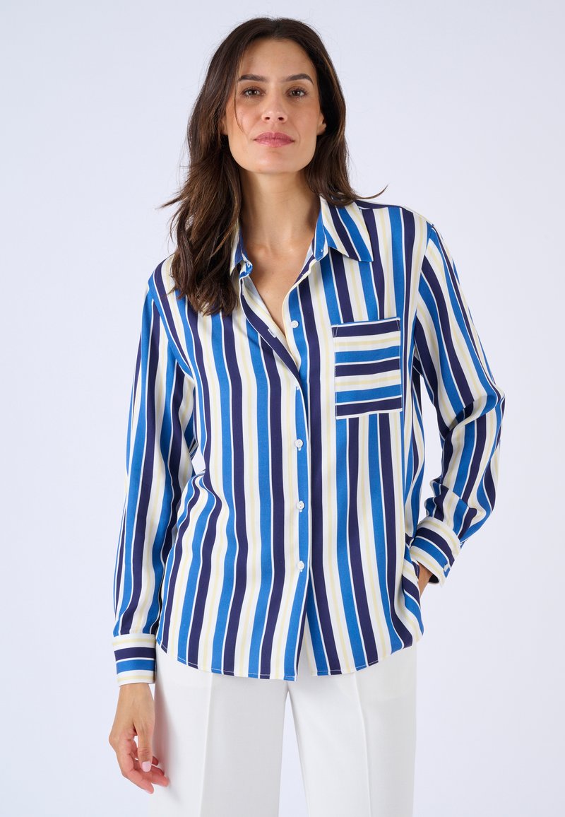 Camisa a rayas con franjas verticales en azul, marino, blanco y amarillo. Incluye un bolsillo en el pecho y cierre de botones, con mangas largas.