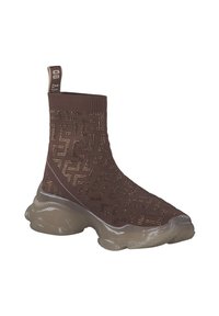Kniehoge bruine sokboot met een gebreide bovenkant in een patroon, metalen accenten en een stevige doorschijnende zool voor extra ondersteuning en stijl.