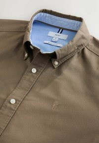 Bruine katoenen overhemd met een button-down kraag, voorzien van een lichtblauwe gestreepte binnenkraag, witte knopen en een klein geborduurd logo.