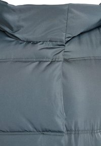 Pelēks pūkains mētelis ar gludu, matētu apdari. Tam ir kapuce un quilted dizains ar horizontālām šuvēm siltumizolācijai.