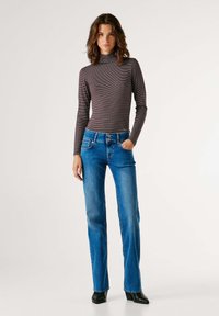 Triibuline, pika varrukaga kõrge kaelusega tumehall ja kreemjas t-särk; sinised flööri lõikega teksad esitaskutega, kahe nupu kinnitusega ja siledapinnaline.