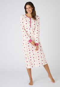 Maglietta da notte a maniche lunghe color crema con motivo a cuori rosa e corallo. Presenta un collo rotondo e una fila di bottoni, con polsini a contrasto.